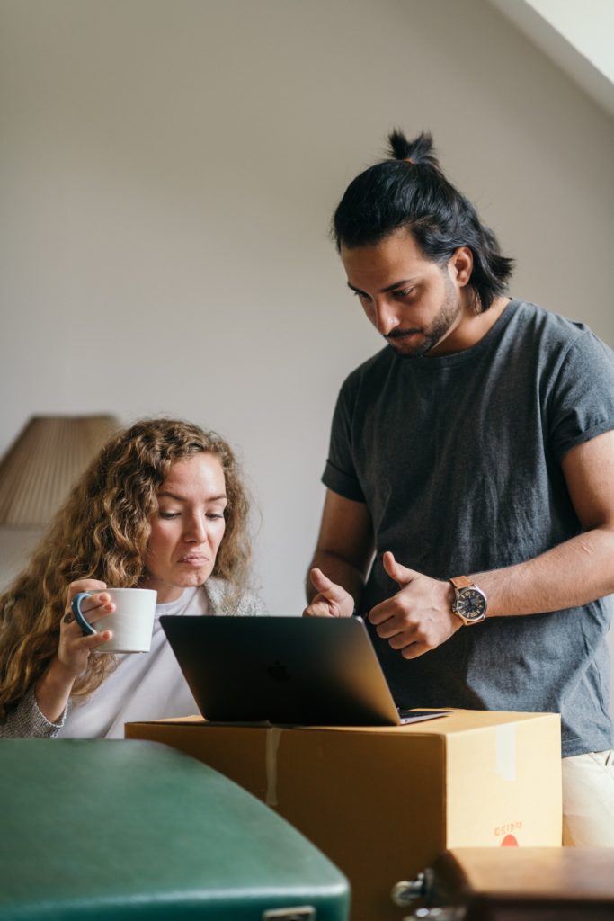 man and woman evaluate something on a laptop computer